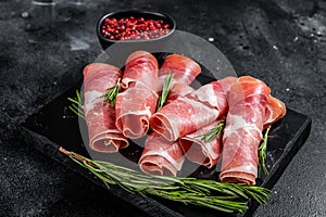 Traditional Spanish Jamon Serrano ham on marble board. Black background. Top view