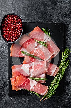 Traditional Spanish Jamon Serrano ham on marble board. Black background. Top view