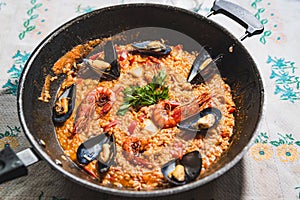 Traditional spanish seafood paella or arroz caldoso inside black pan with shrimps, mussels, clams and parsley. Homemade