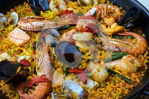 Traditional spanish seafood paella dish in a black pan. Mussels, Amandi and prawns on a pillow of rice. Close-up.