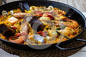 Traditional spanish seafood paella dish in a black pan. Mussels, Amandi and prawns on a pillow of rice. Close-up.
