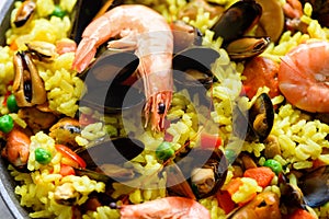 Traditional spanish seafood paella in pan rice, peas, shrimps, mussels, squid on light grey concrete background. Top