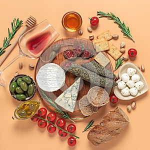 Traditional Spanish tapas or Italian antipasti on a pastel peach background. Various Mediterranean snacks with wine. Top view,