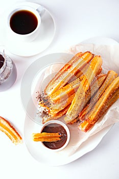 Traditional Spanish treat street fast food churros on a plate with hot chocolate sauce