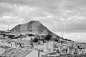 Traditional Spanish whitewashed village with mountain and ruined castle on the sumit. Monochrome black and white