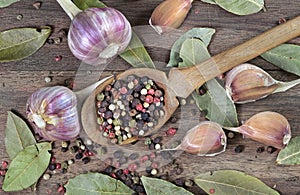 traditional spices for the kitchen. bay leaf, mixture of various peppers in a spoon and garlic on a wooden table. top view