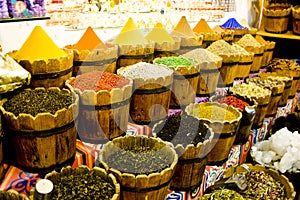 Traditional spices market - pots and wooden tubs stand in row with tea, spices, fruits, roots, flowers. Street bazaar