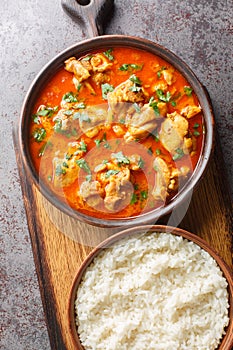 Traditional spicy Lahori Chicken Curry served with rice closeup on the wooden board on the table. Vertical top view