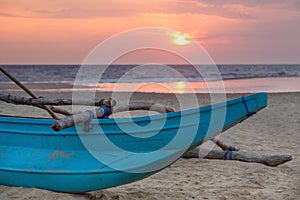 Traditional Sri Lankan fishing boat on sandy beach at sunset.