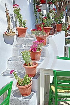 Traditional stairs with flower pots and green chair at Ano Koufonisi island Greece