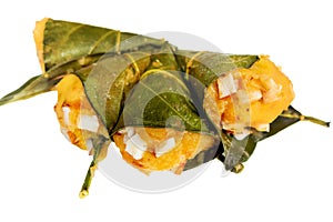 Traditional steamed ripe palmyra palm fruit cake wrapped with jackfruit leaves and sprinkled with coconut pieces.