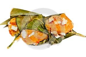 Traditional steamed ripe palmyra palm fruit cake wrapped with jackfruit leaves and sprinkled with coconut pieces.