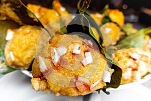 Traditional steamed ripe palmyra palm fruit cake wrapped with jackfruit leaves and sprinkled with coconut pieces.