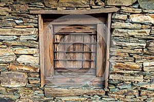 Traditional stone hut in Uttarakhand, India, featuring a wooden window set within a rugged stone wall, showcasing local