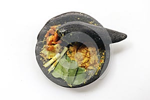 Traditional stone mortar and pestle from Asia with spicy ingredients chilli, yellow seasoning, leaf, leak leaf from Indonesia