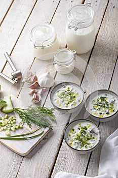 Traditional summer cold soup of homemade yogurt, cucumbers and fresh herbs on a table