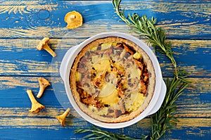 Traditional swedish chanterelle mushrooms tart - quiche with cheese and herbs in the baking dish decorated with fresh rosemary