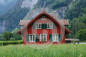 Traditional swiss manor red country house in switzerland with lush green surroundings