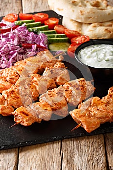 Traditional Taouk chicken kebab with fresh salad, yogurt sauce and pita bread close-up. vertical photo