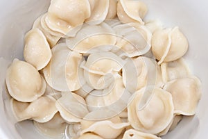 Traditional tasty boiled russian pelmeni, ravioli, dumplings with meat on white ceramic plate on grey background