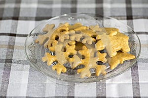 Traditional tasty Czech gingerbreads, Christmas snowflakes and reindeer on glass plate on grey chequered tablecloth