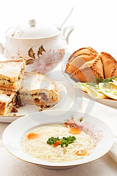 Traditional Tatar holiday table. Tokmach - noodle soup with chicken. Triangles - meat pies and sweet cake.
