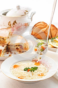 Traditional Tatar holiday table. Tokmach - noodle soup with chicken. Triangles - meat pies and sweet cake.