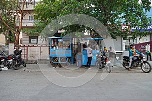 Traditional tea house in the streets of India. Tea vendor preparing tea and buyer maintaining distance with mask on face. India