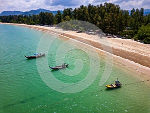 Traditional Thai Longtail fishing boats anchored off a small, palm tree lined tropical beach (Khao Lak, Thailand