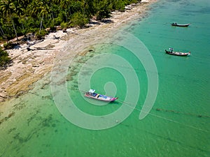 Traditional Thai Longtail fishing boats anchored off a small, palm tree lined tropical beach (Khao Lak, Thailand