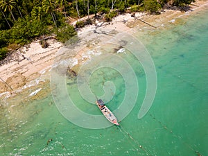 Traditional Thai Longtail fishing boats anchored off a small, palm tree lined tropical beach (Khao Lak, Thailand