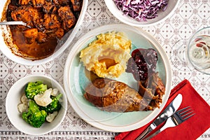 Traditional Thanksgiving dinner with roasted turkey, mashed potatoes, cranberry sause and veggies served on plates