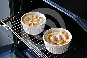 A traditional Thanksgiving dish, sweet potato casserole with marshmallows in portioned forms in the oven. American cuisine