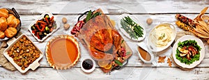 Traditional Thanksgiving turkey dinner above table scene on a rustic white wood banner