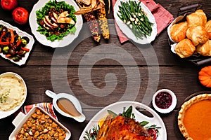 Traditional Thanksgiving turkey dinner. Overhead view frame on a dark wood background.