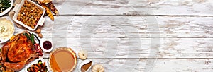Traditional Thanksgiving turkey dinner. Top view corner border on a rustic white wood banner background.