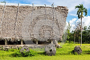 Traditional thatched yapese men`s meeting house called faluw fale and a bank of stone money rai. Yap island, Micronesia, Oceania photo