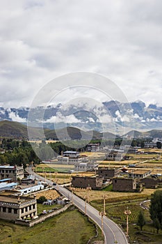 Traditional Tibetan countryside with fields and mountains around Daocheng