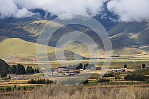 Traditional Tibetan countryside with fields and mountains around Daocheng