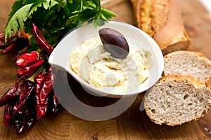 Traditional Tirokafteri in white plate decorated with chili, white bread and parsley.