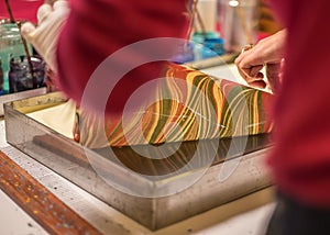 Traditional Turkish art Ebru in process. Woman picking up the finished artwork from the ebru tray with water.