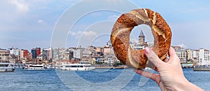 Traditional Turkish bagel simit in a female hand on the background of the panorama of Istanbul and the Galata Tower photo
