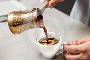 Traditional Turkish Coffee Being Poured From Copper Cezve Into White Cup
