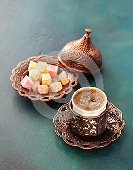 Traditional turkish coffee and turkish delight on dark green wooden background