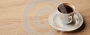 Traditional turkish coffee in patterned white cup on oak coffee table