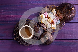 Traditional turkish coffee and turkish delight on dark violet wooden background. Flat lay