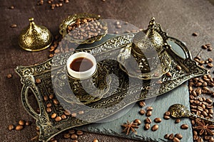 Traditional turkish coffee in vintage cup in metal service, anise, roasted beans on brown background 2