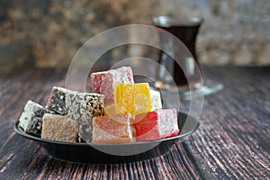 Traditional turkish delight and glass for tea bardak on dark wooden background