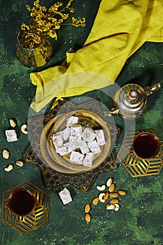 traditional Turkish delight (lokum) with arabic tea and gypsophila vase on green grunge .