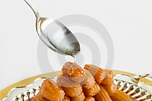 Traditional Turkish Fried Dough Dessert,Tulumba,puring syrup with spoon on the shiny metal tray.